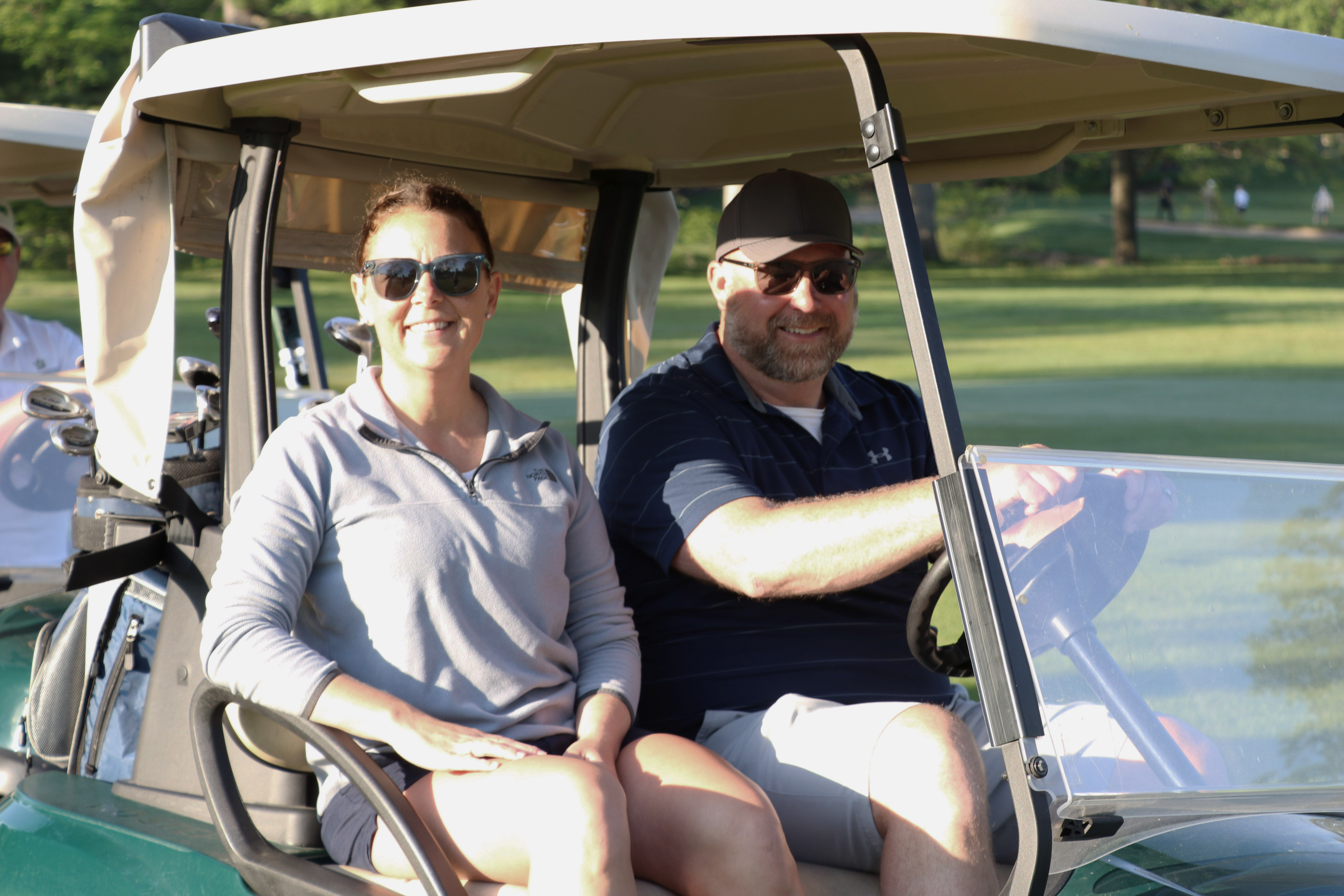 nick and stacy graymire smiling in golf cart