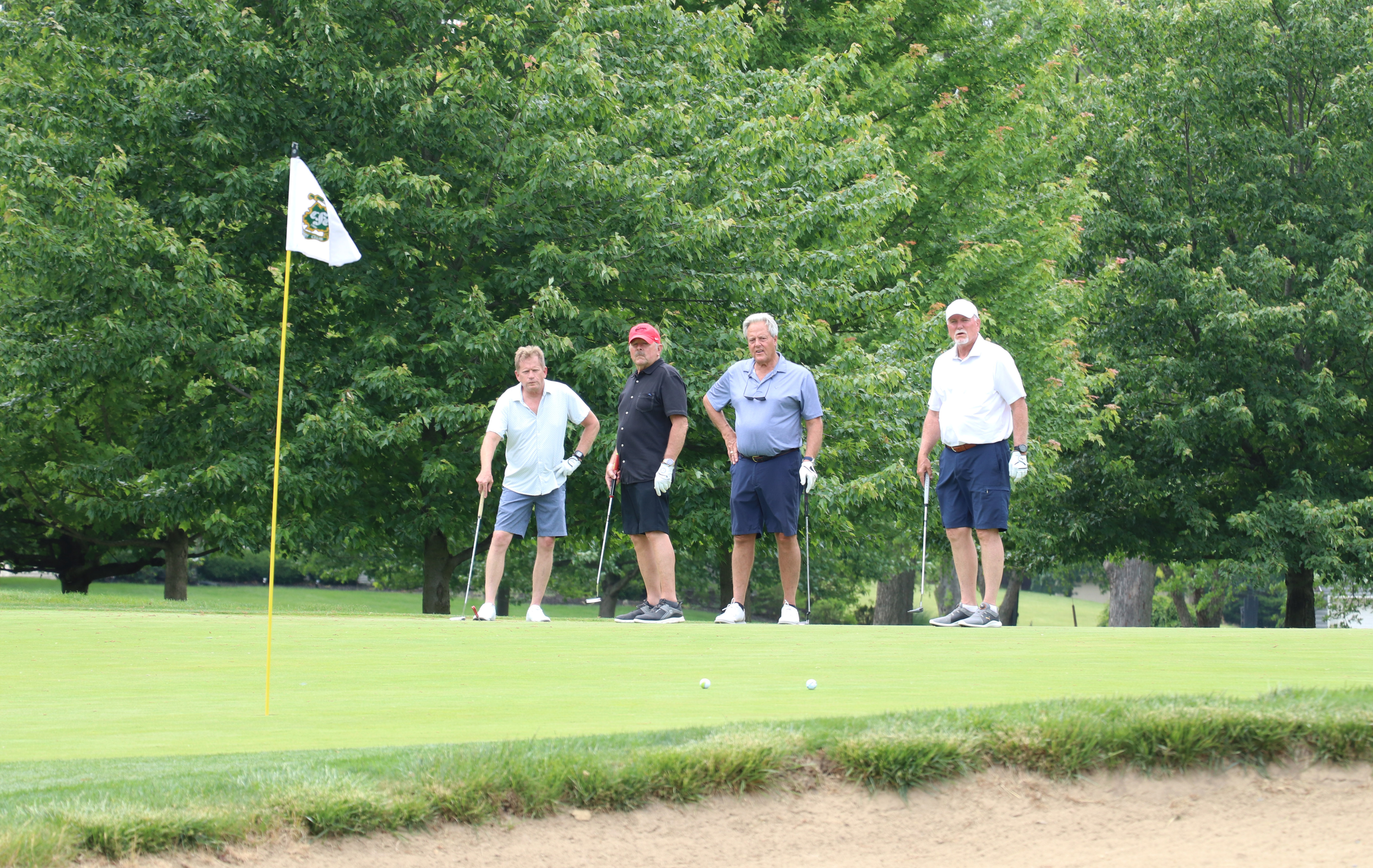golfers watching golf ball on the green