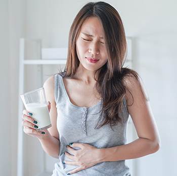 asian woman holding stomach after drinking milk