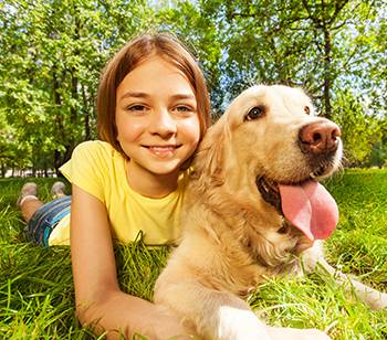 young girl with dog laying on the grass